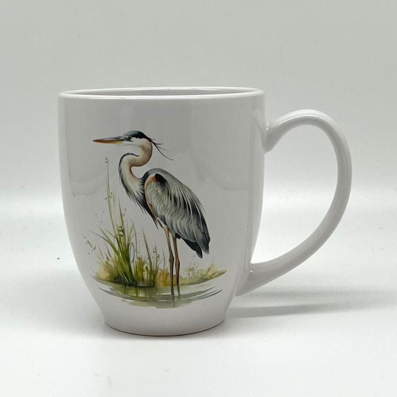 White 16-ounce stoneware bistro mug featuring a graceful blue heron standing beside green marsh grasses and reflective water.