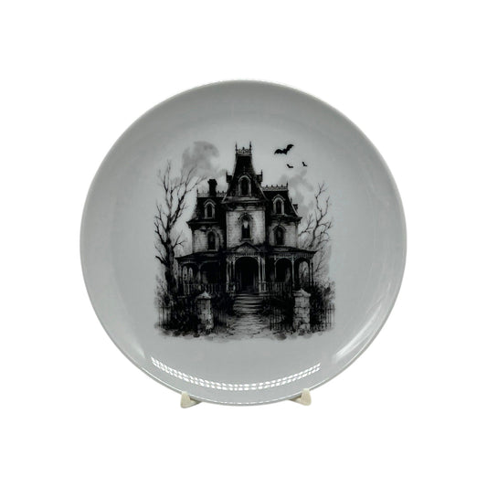 Haunted Manor 6.25 inch Halloween coupe plate with black-and-white Victorian haunted house, bare trees, wrought-iron gate and flying bats