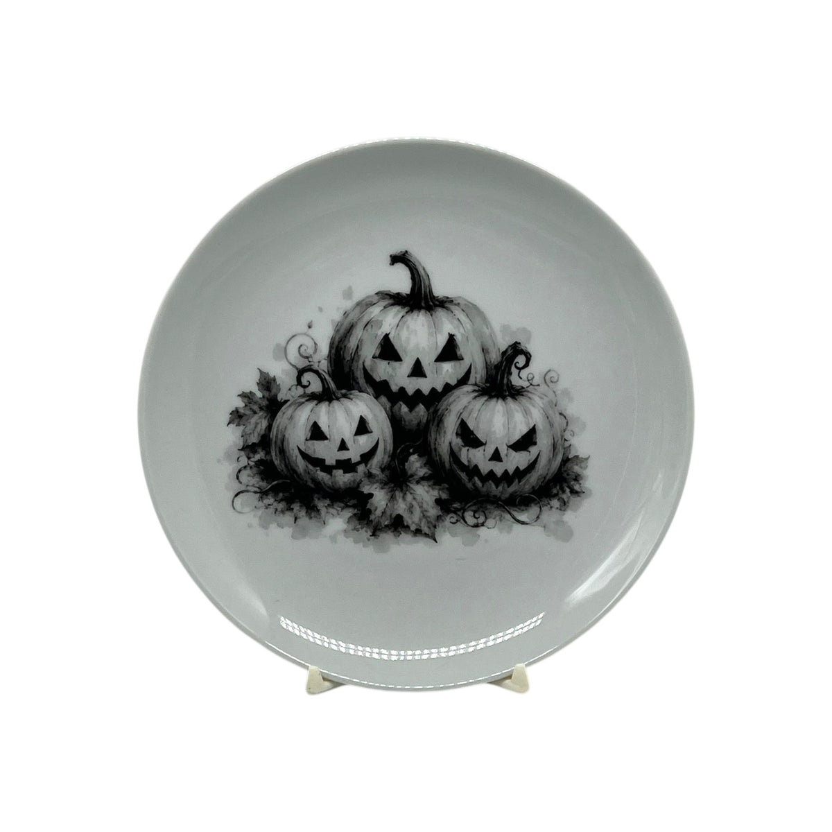 Shop the 6.25" Jack-O’-Lantern Trio Halloween Coupe Plate featuring three carved pumpkins in striking black-and-white artwork. Perfect for spooky entertaining.